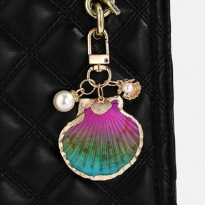 Macro detail of gradient seashell keychain with faux pearl on black leather background