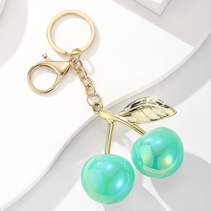 Close-up of golden leaf charms and iridescent mint green cherry beads on a sleek keychain