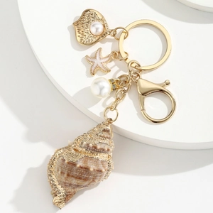 Golden sea shell and starfish keychain with white pearl on a minimalist pedestal