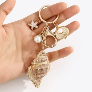 Detail view of gold ocean keychain with natural seashell, starfish and pearl charms