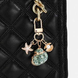 Detailed shot of ocean-themed seashell and starfish charms on a black quilted bag