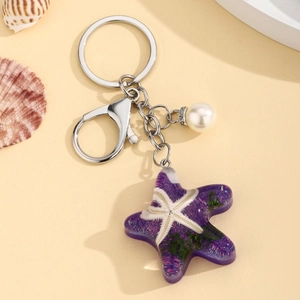 Ocean starfish keychain with purple resin charm and white faux pearl on beige background