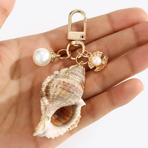 Detailed view of ocean-themed keychain featuring natural conch, faux pearl, and gold shell charm