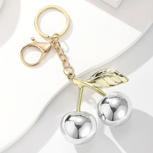 Detailed view of mirror-polished gold and silver metallic cherry keychain with leaves