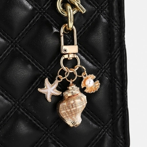 Detail showing golden starfish, seashell, and pearl charms on a black leather bag