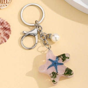 Detail of pink resin starfish keychain with internal sea decorations and a pearl charm