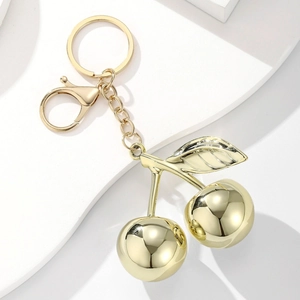 Glossy golden cherry resin keychain with metallic ring on a minimalist white background
