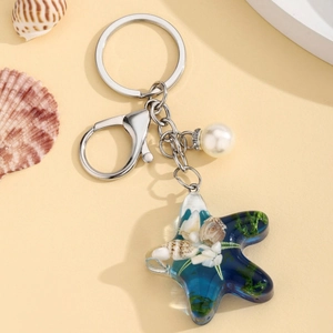 Close-up of ocean-themed starfish keychain with embedded shells, algae and white pearl