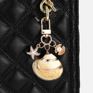 Close-up of golden shell and starfish charms on a black quilted leather handbag
