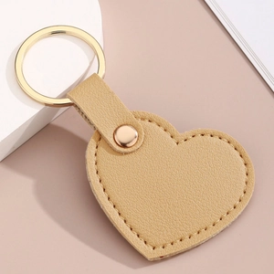 Détail d'un porte-clés coeur en similicuir marron clair avec couture et anneau doré
