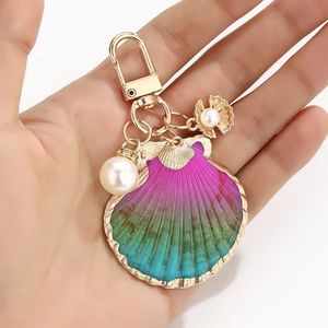 Detail of a gradient shell keychain with gold edges and a large white pearl pendant