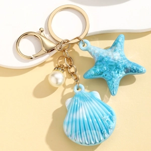 Detail of seashell keychain with starfish, pearl, gold lobster clasp and blue striped charm