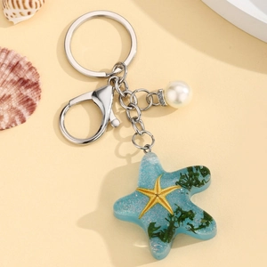 Detailed view of ocean-themed resin starfish keychain with embedded sea algae and white pearl