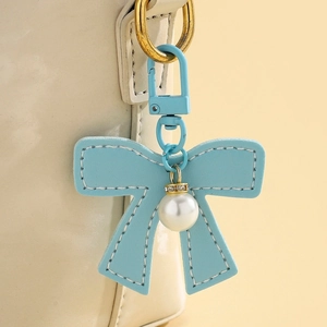 Detail of light blue leather bow charm with white pearl pendant and metal lobster clasp