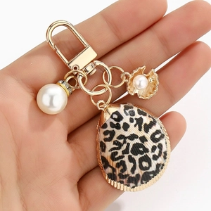 Close-up of golden leopard print shell keychain with pearls and lobster clasp charm