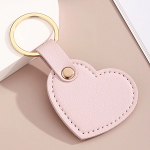 Vue détaillée du porte-clés cœur en cuir rose avec texture litchi et anneau doré
