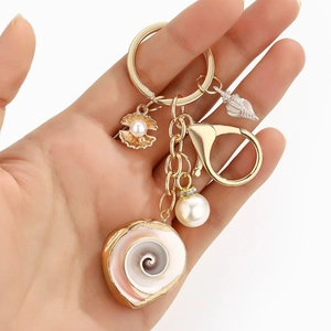 Detailed close-up of golden keychain with natural conch, pearls, and seashells