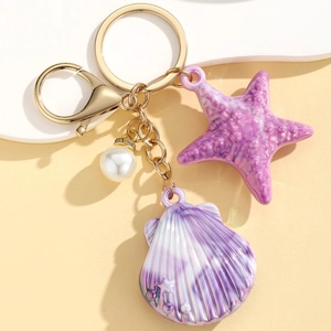 Detail of purple resin starfish and shell keychain with golden hardware and white pearl charm