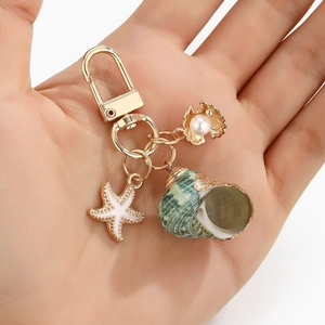 Handheld ocean-themed keychain with natural conch, starfish, and pearl in gold finish