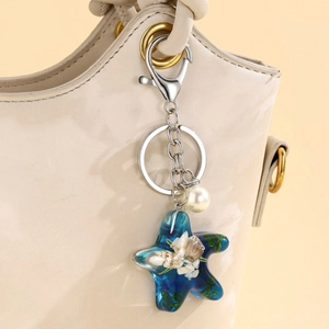 Macro view of blue resin starfish keychain with shells and pearls on a leather bag