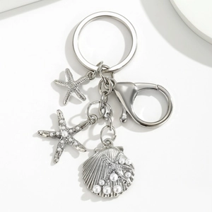 Macro detail of silver marine keychain with starfish charms and white pearl accents