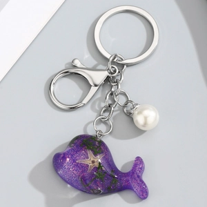Détail du porte-clés baleine en résine violette avec motif étoile de mer et perle