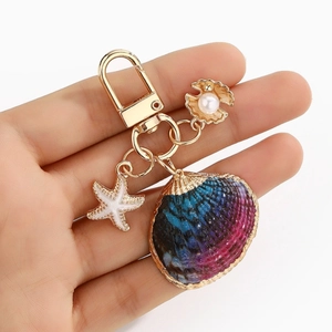 Detail of seashell keychain with blue gradient shell, starfish charm, and white pearl