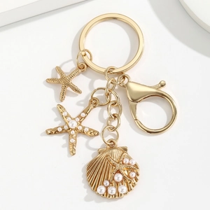 Golden ocean theme keychain with starfish, seashell, and pearls on a white background