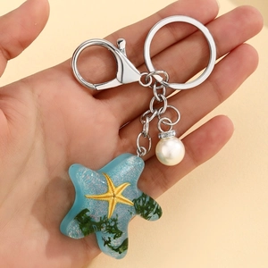 Detailed macro view of a blue resin starfish keychain with pearl and metallic lobster clasp