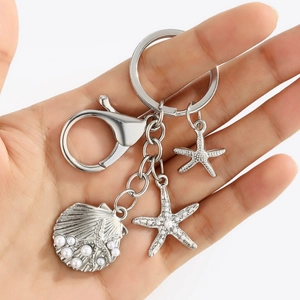 Marine life keychain featuring silver starfish and a pearl-inlaid scallop shell pendant