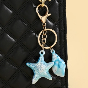 Detail von buntem Seestern- und Muschelanhänger an einer schwarzen Stepptasche