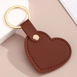 Vue détaillée du porte-clés cœur en cuir marron avec anneau doré et coutures précises