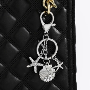 Starfish and shell keychain with pearls on a black quilted leather handbag