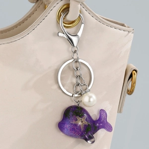 Détail d'un porte-clés baleine en résine violette avec incrustation d'étoile de mer