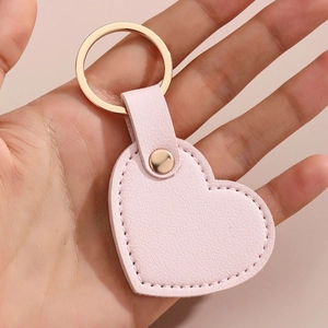 Porte-clés créatif en cuir rose clair en forme de cœur avec anneau doré en main