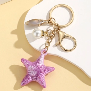 Detailed shot of purple starfish keychain with pearl and shell charms on golden hardware