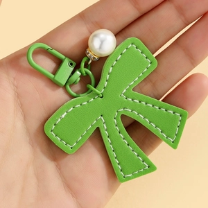 Detail of green leather K-letter keychain with white stitching and pearl charm