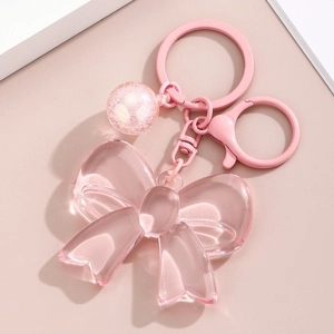 Detail of pink resin bow keychain with glossy metal ring and decorative glitter bead