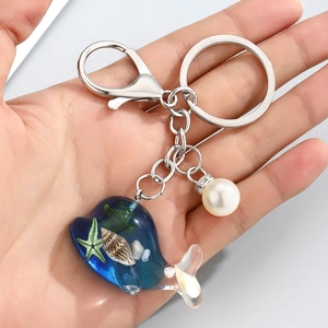 Détails du porte-clés baleine en résine avec étoiles de mer et perle blanche