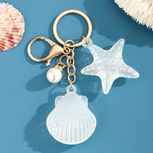 Détail d'un porte-clés marin avec coquillage, étoile de mer et perle sur fond bleu