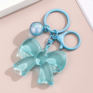 Detailed close-up of light blue acrylic bow keychain with sequins in a clear round charm