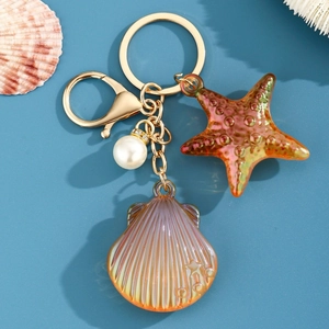 Détail d'un porte-clés marin avec étoile de mer et coquillage en résine sur fond bleu été