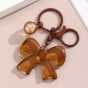 Detailed macro view of amber acrylic bow keychain with transparent glitter ball charm