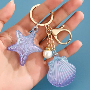 Détails du porte-clés thème marin avec étoile de mer violette, coquillage et fermoir doré