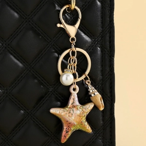 Close-up of a pearlescent gradient starfish keychain on a black quilted leather bag
