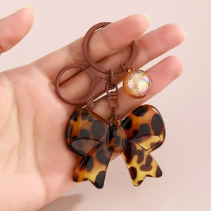 Detail of leopard print bow keychain with matte brown ring and glitter ball charm