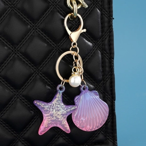 Porte-clés océan en résine avec étoile de mer et coquillage sur un sac à main