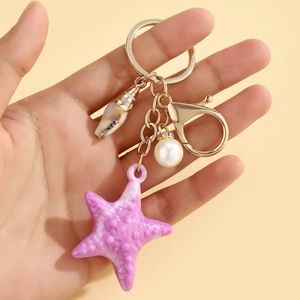 Purple starfish keychain with white pearl and conch pendant on a gold lobster clasp
