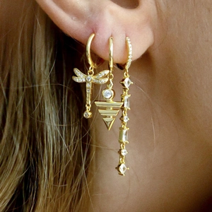 Makroaufnahme von dreiteiligem goldenem Ohrring-Set mit Libellen-Anhänger und Zirkonia