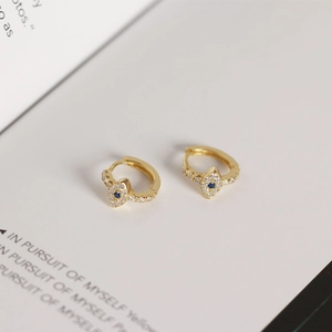 Vue détaillée de boucles d'oreilles Evil Eye dorées avec cristal bleu et zircons pavés